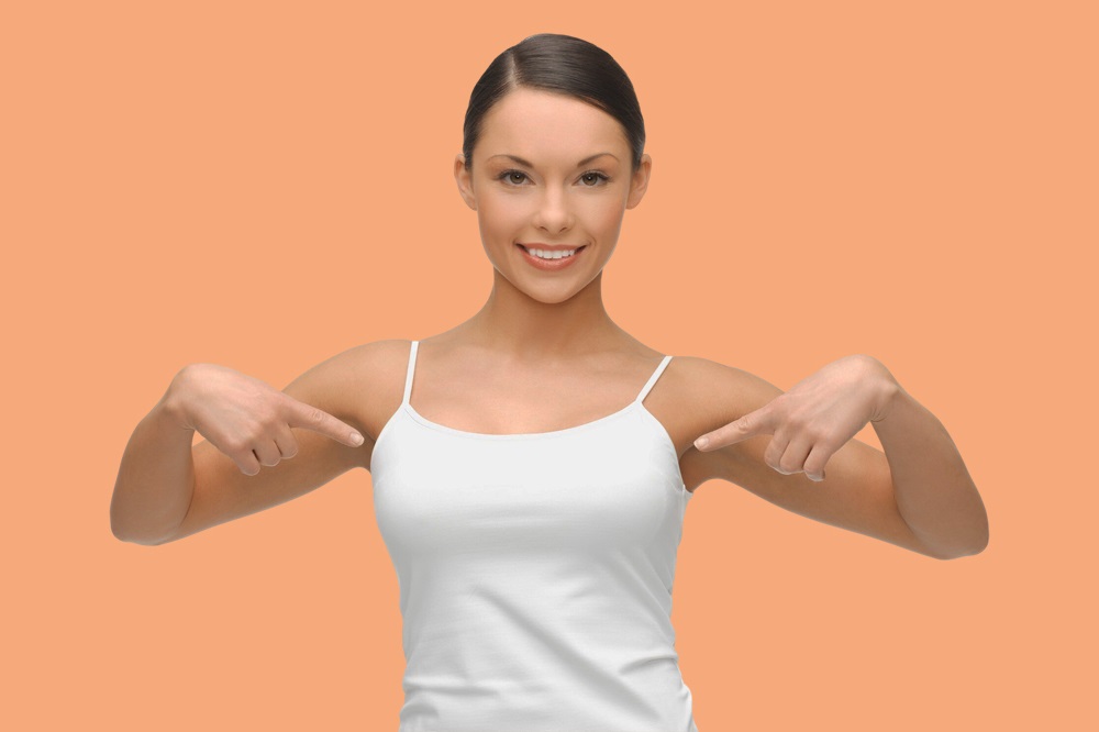 Woman pointing at her breasts after lift surgery