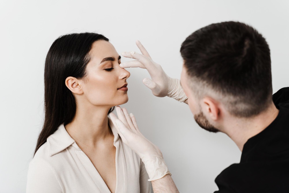 Doctor examining woman’s nose after rhinoplasty