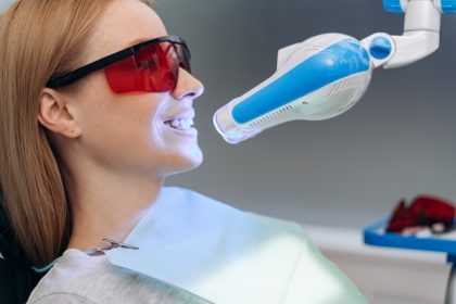 Woman undergoing professional teeth whitening procedure with LED light device